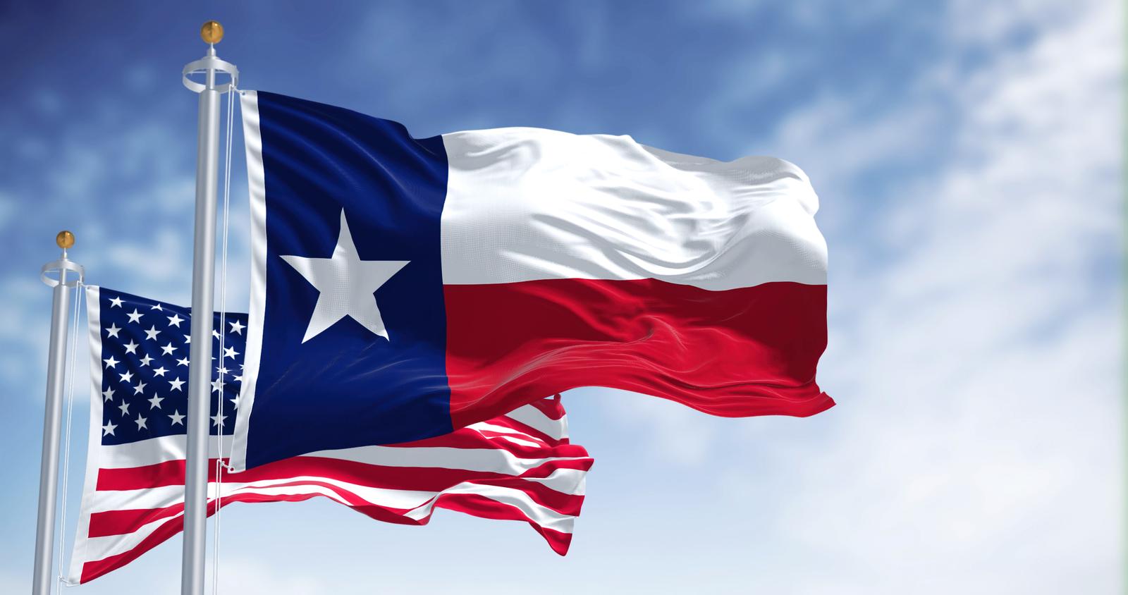 The Texas state flag waving along with the national flag of the United States of America. Texas s a state in the South Central region of the United States